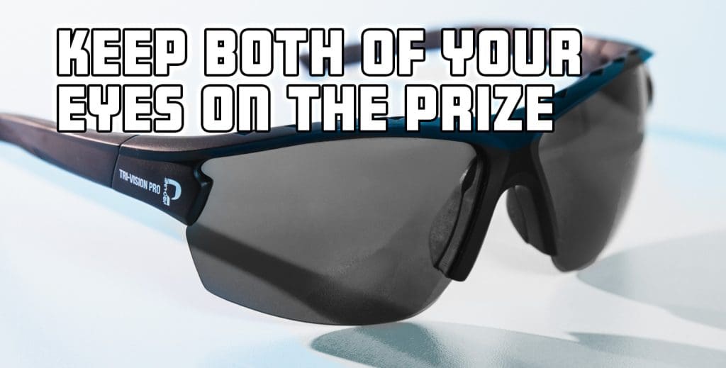 Close-up of a pair of dark-lens sports sunglasses labeled "Tri-Vision Pro" with bold overlay text that reads: "KEEP BOTH OF YOUR EYES ON THE PRIZE." The sunglasses rest on a white surface with a soft blue tint.